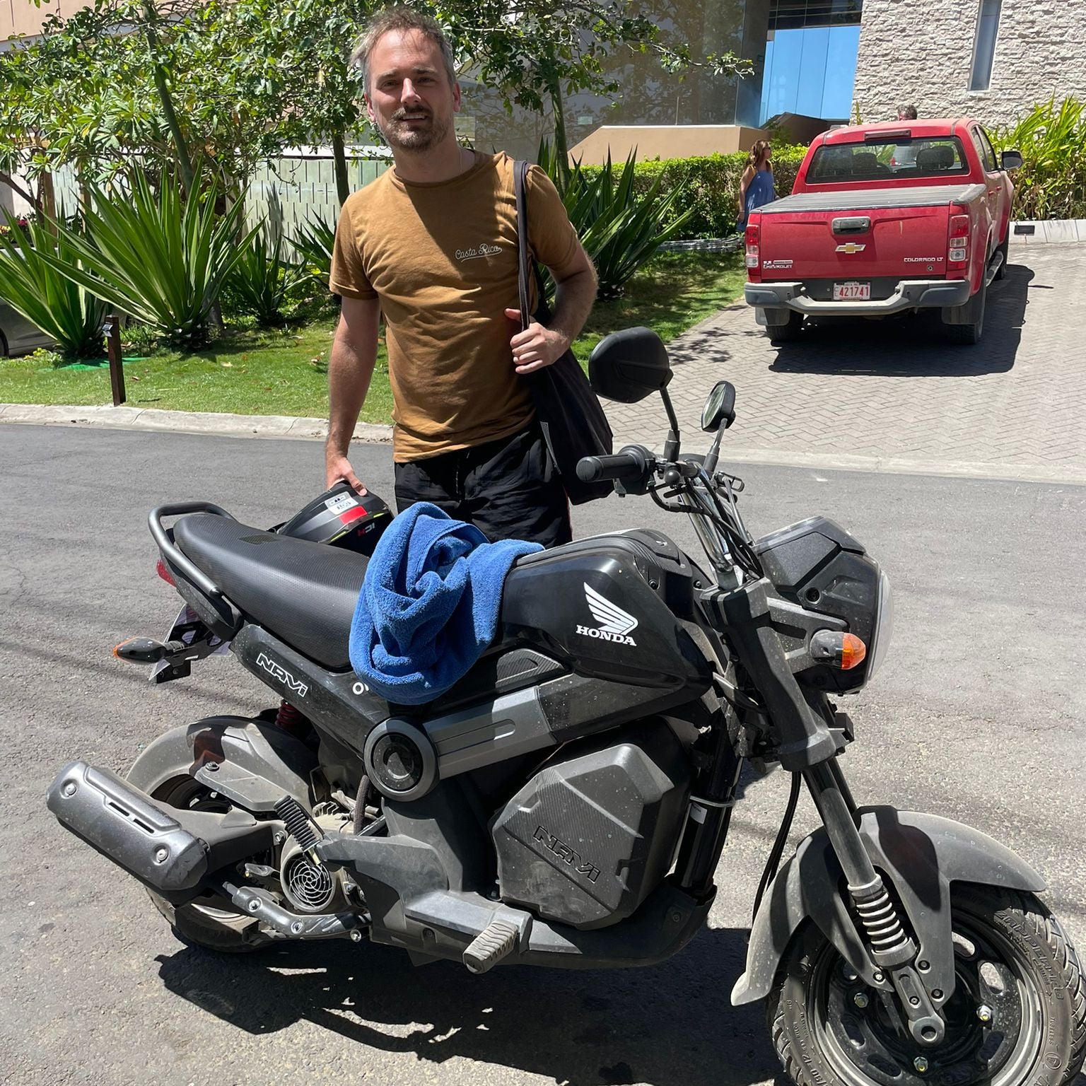 Ohana Rental Tamarindo Client Testimonial of James Lee standing next to a Honda Navi Scooter on a road along Tamarindo Heights