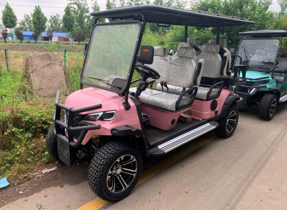 Pink golf cart on a paved road with trees and grass in the background